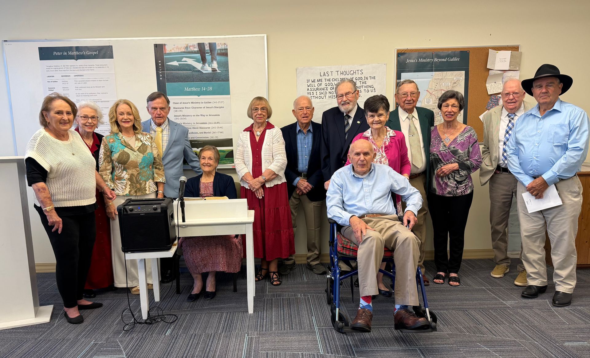 Group posing in a meeting room, with posters on the wall and one man seated in a wheelchair.
