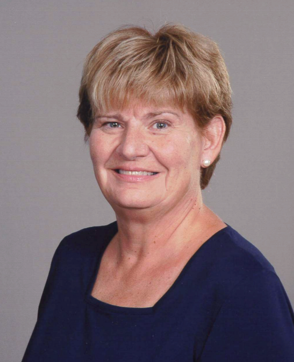 Smiling woman in a navy top against a plain gray background