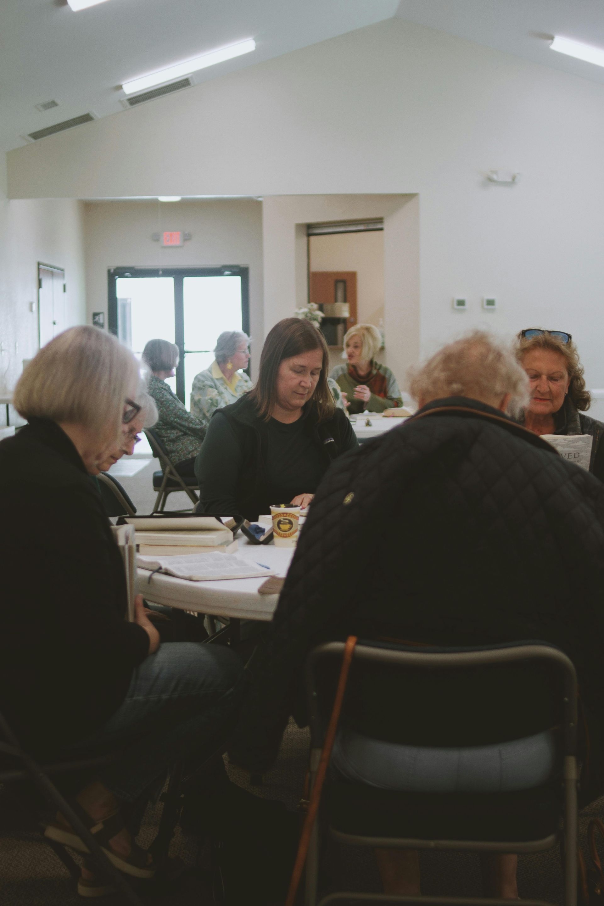People seated around a table in a bright meeting room, talking and eating together