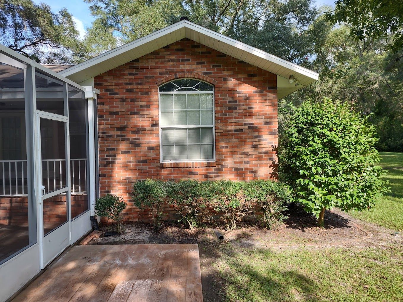 A brick house with a screened in porch and a window.