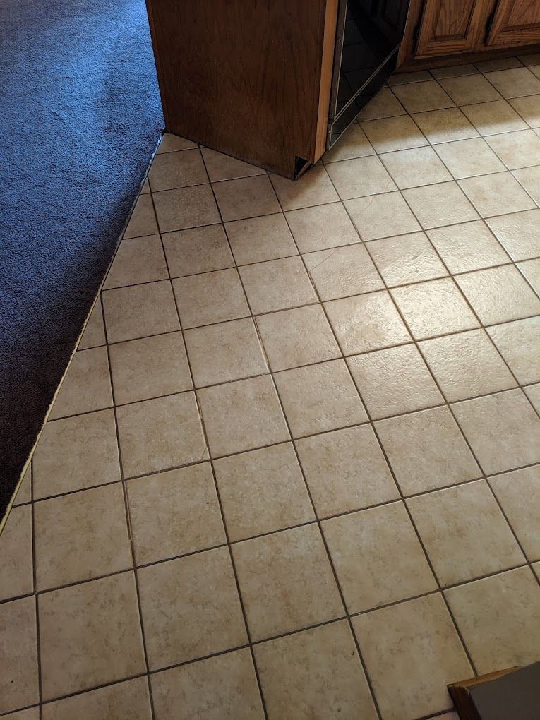 A kitchen floor with tiles and a wooden cabinet