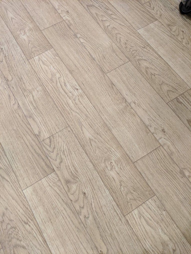 A close up of a wooden floor with a chair in the background.