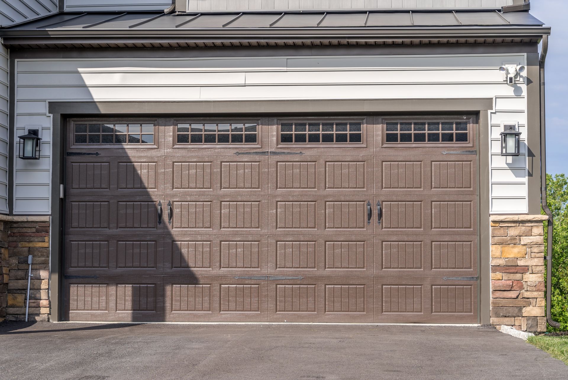 Brown insulated steel residential garage door with window inserts