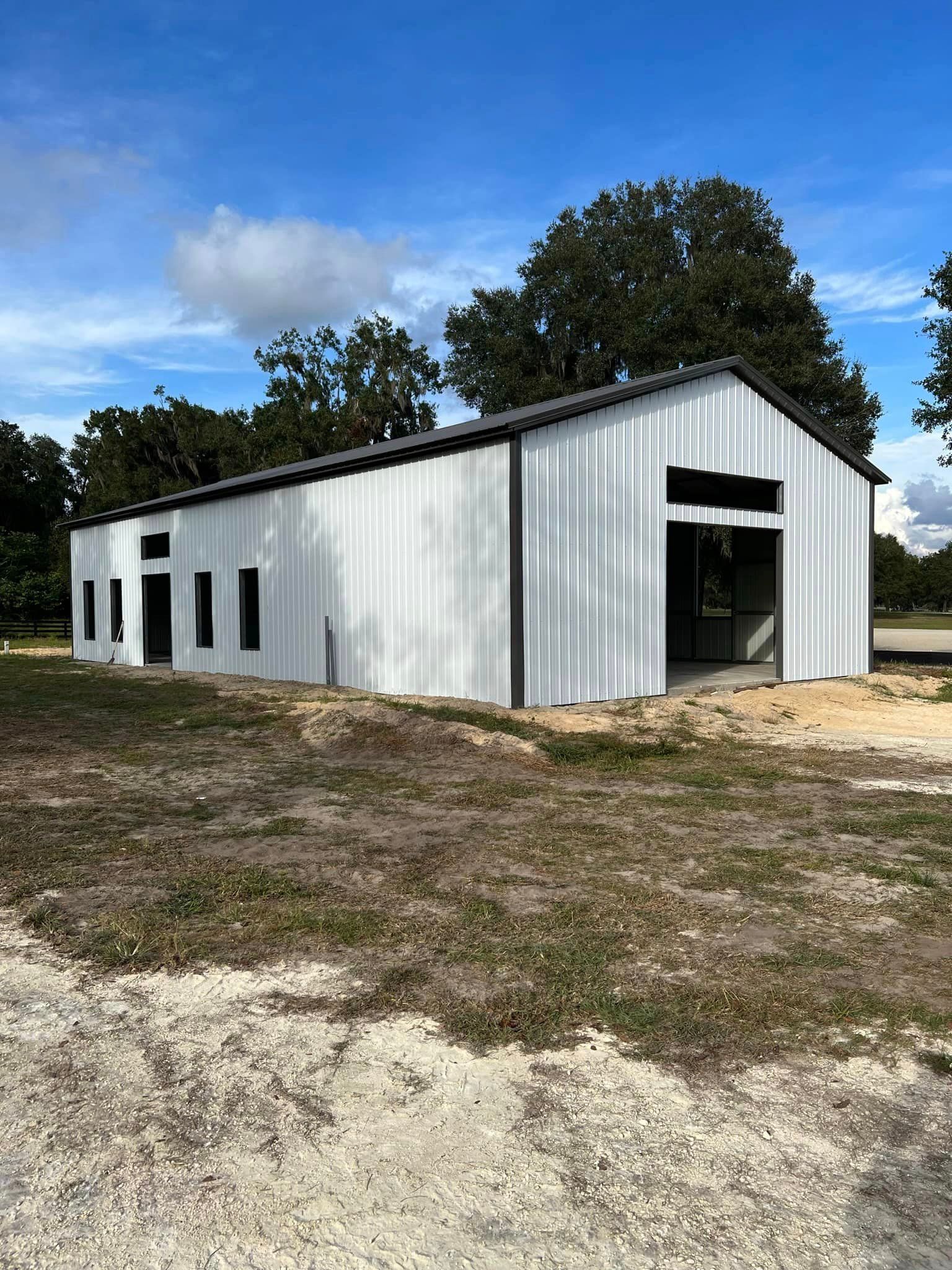 A large white building is sitting in the middle of a field.