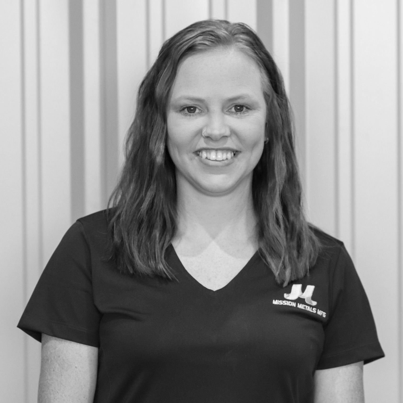 A woman in a black shirt is smiling in a black and white photo.