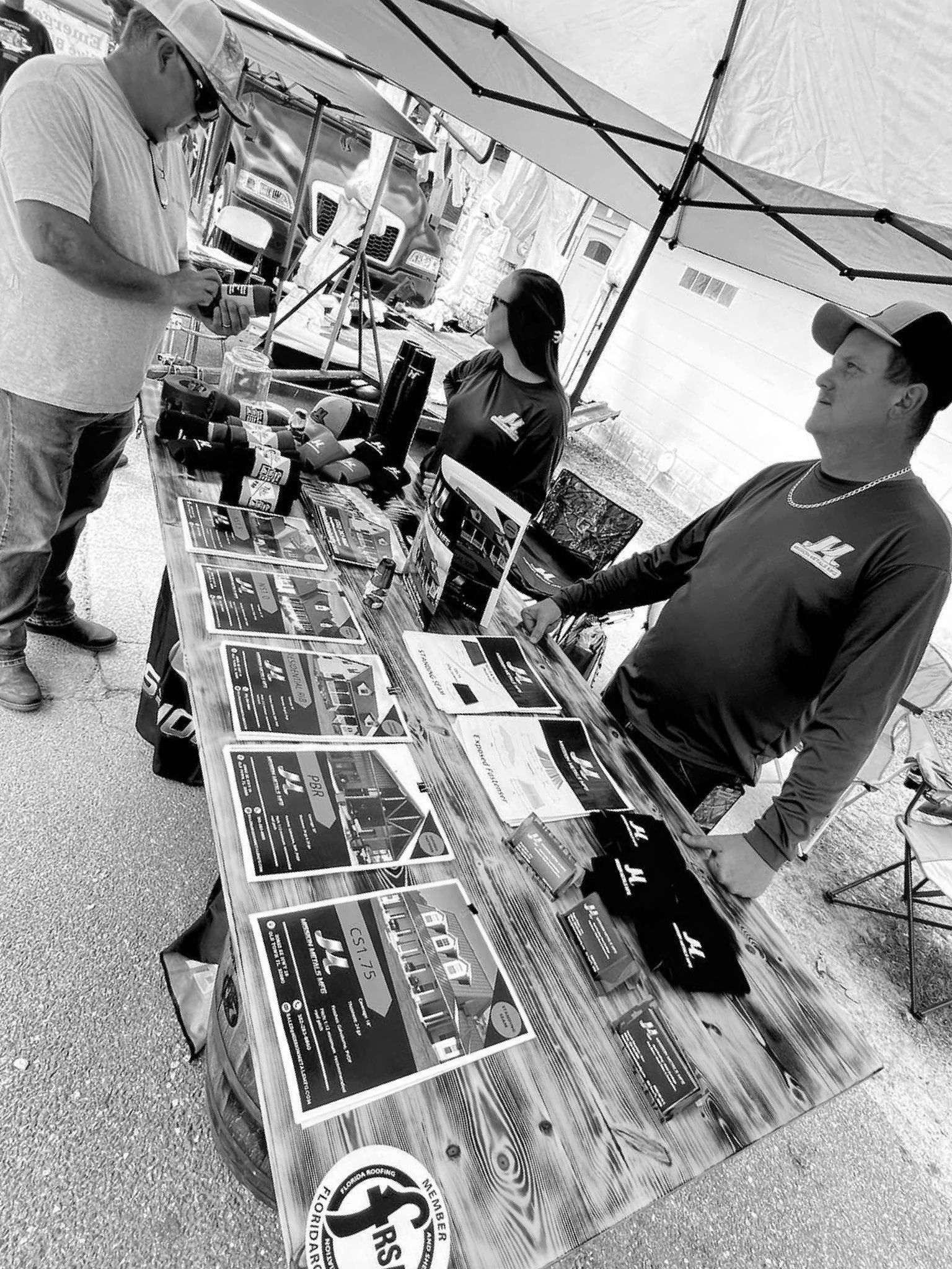 A black and white photo of a group of people standing around a table.