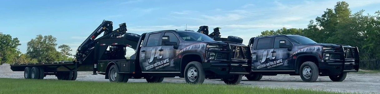 Three black armored vehicles on a flatbed trailer, parked outdoors under a clear sky