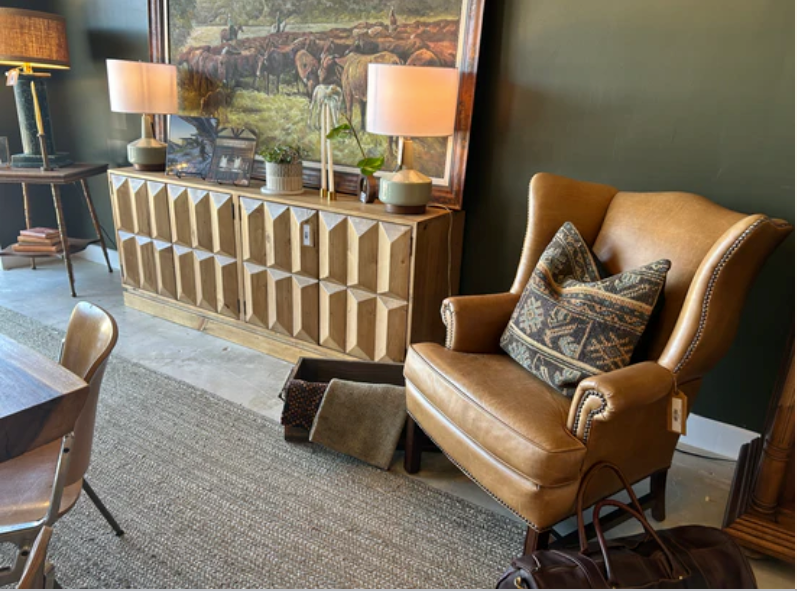 Elegant lounge with tan leather chair, patterned rug, lamps, and scenic wall art