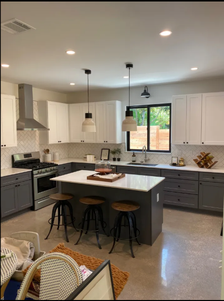 Modern kitchen with white cabinets, gray island, pendant lights, and black bar stools