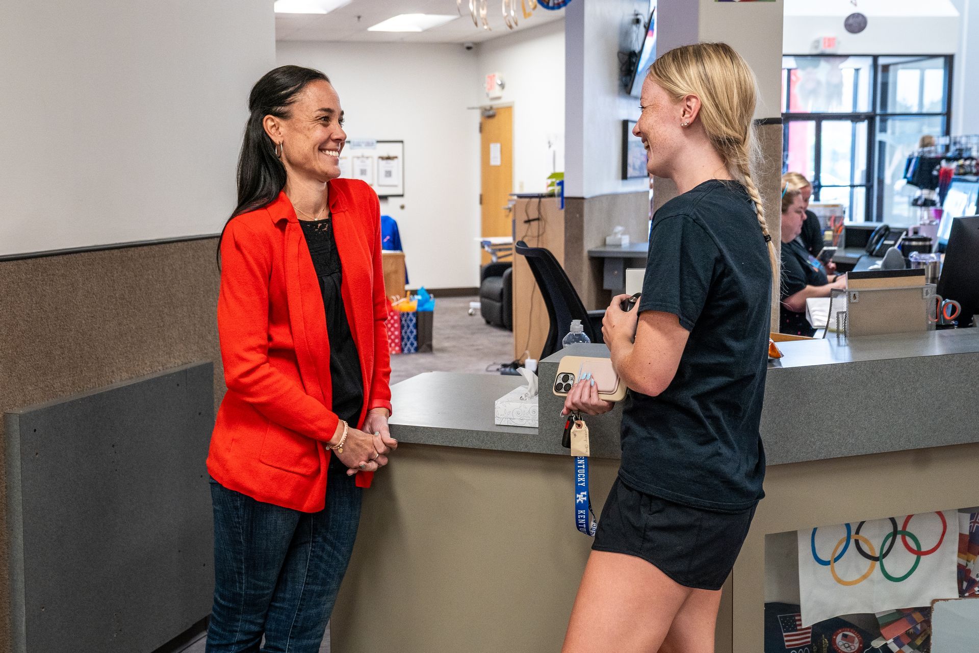 Two women are standing at a counter talking to each other.