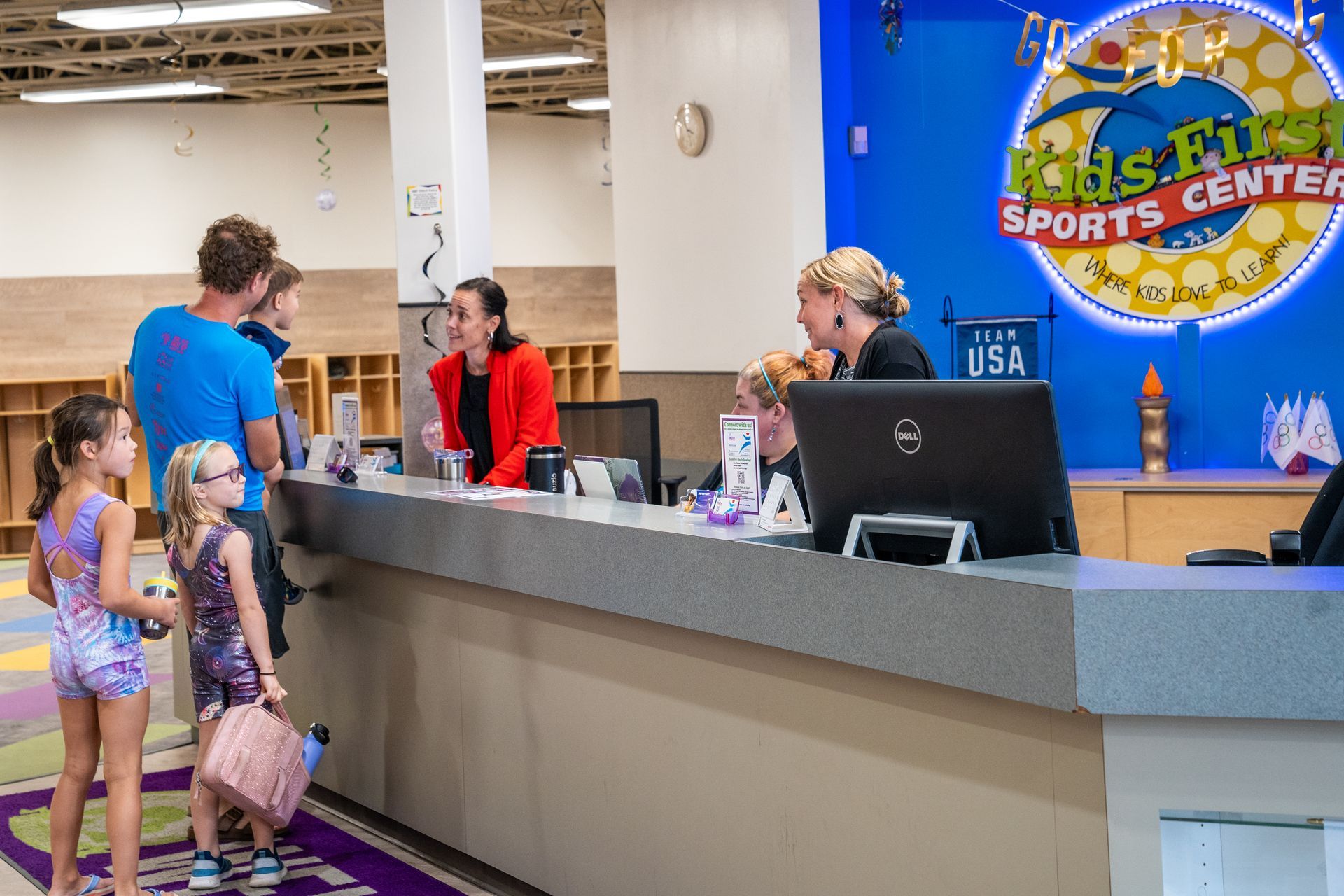A group of people are standing at a counter in a sports center.