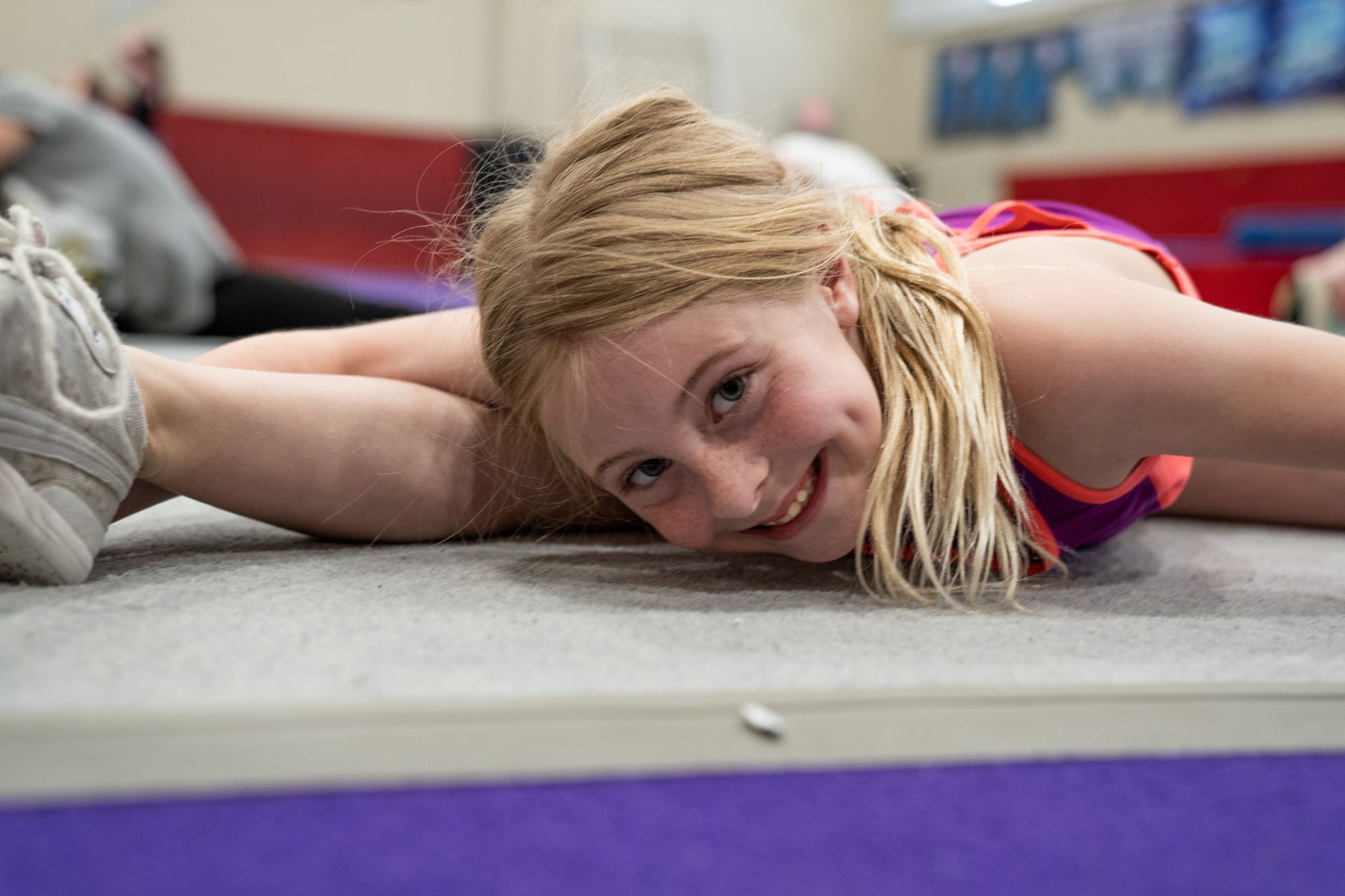 Smiling athlete lying on a mat in a gym, stretching on the floor