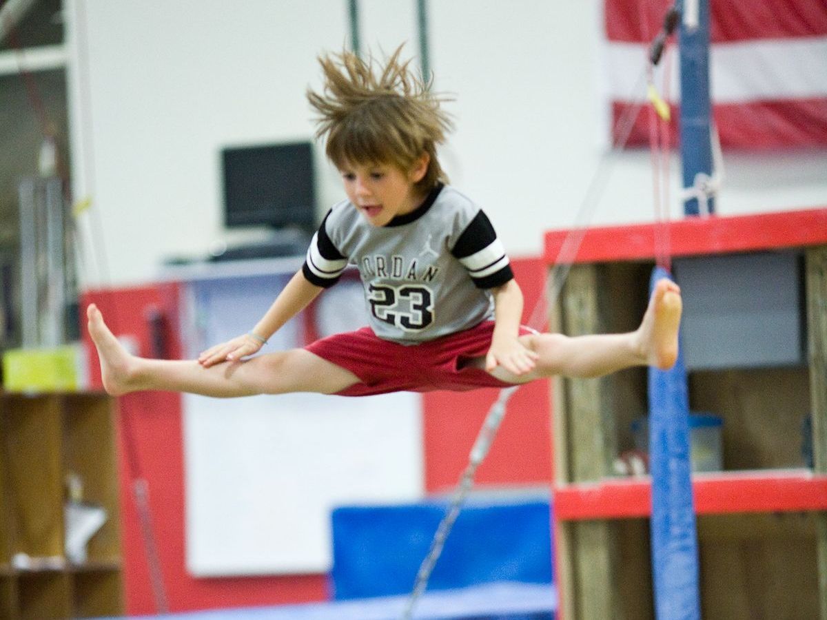 Gymnast doing a split leap on a balance beam in an indoor gym