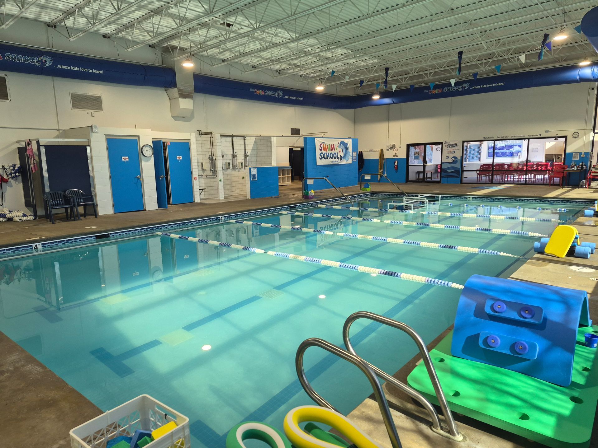 Indoor swimming pool with lanes and diving platform; blue and white accents.