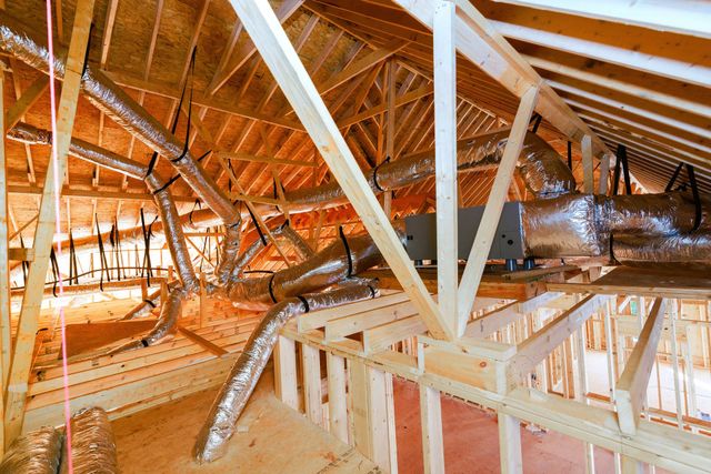 Attic under construction with exposed wooden beams, insulation, and roof framing.