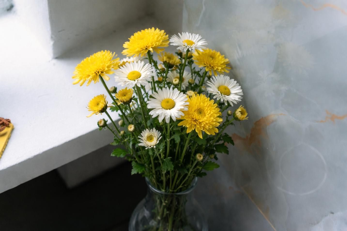 Fresh yellow and white daisies arranged in a glass vase, symbolizing simple, heartfelt remembrance in Indian Rocks Beach, FL.