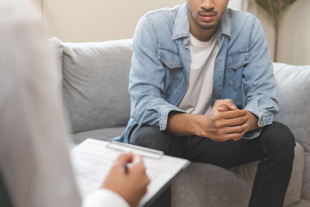 A Woman Is Sitting On A Couch Talking To A Man — Noosa Psychological Services in Noosa Heads, QLD