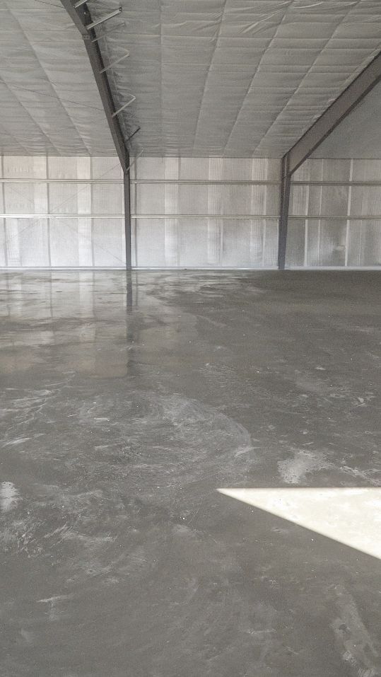 Empty warehouse interior with concrete floor and insulated metal walls under a curved ceiling