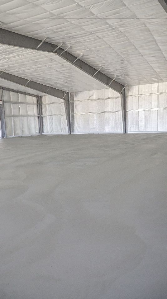 Empty white indoor event tent with high arched ceiling and concrete floor