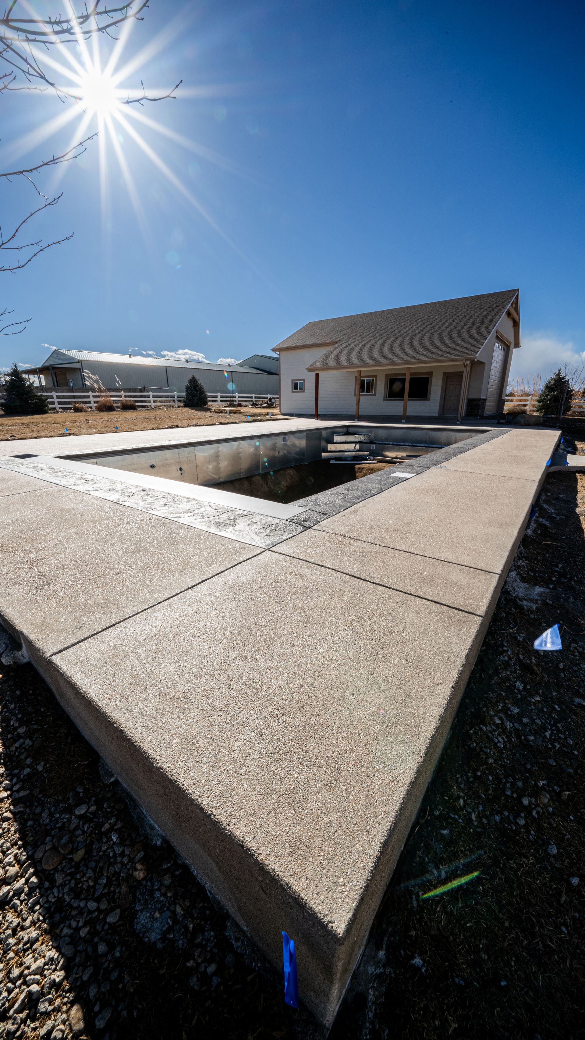 Modern concrete fountain plaza with a house in the background under a bright sunlit blue sky