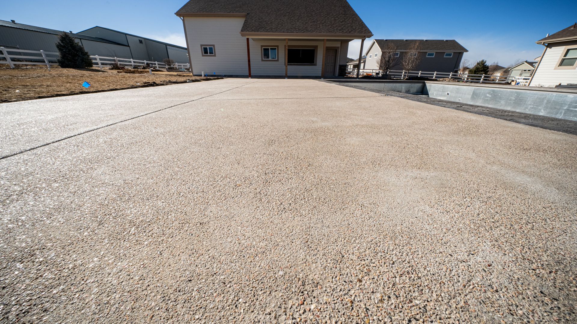 New concrete driveway leading to a house under construction in a suburban neighborhood