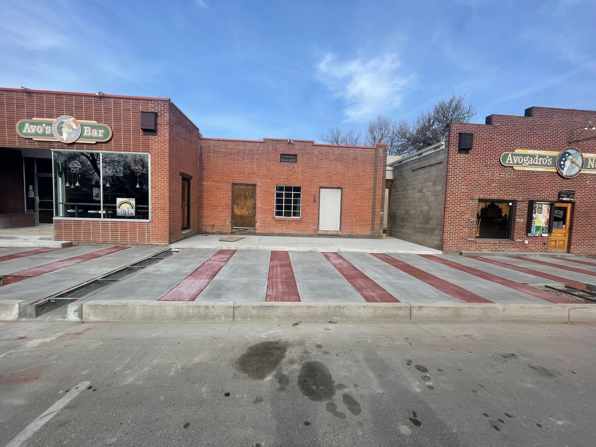 Brick storefronts with a striped crosswalk in front and two shop entrances on either side