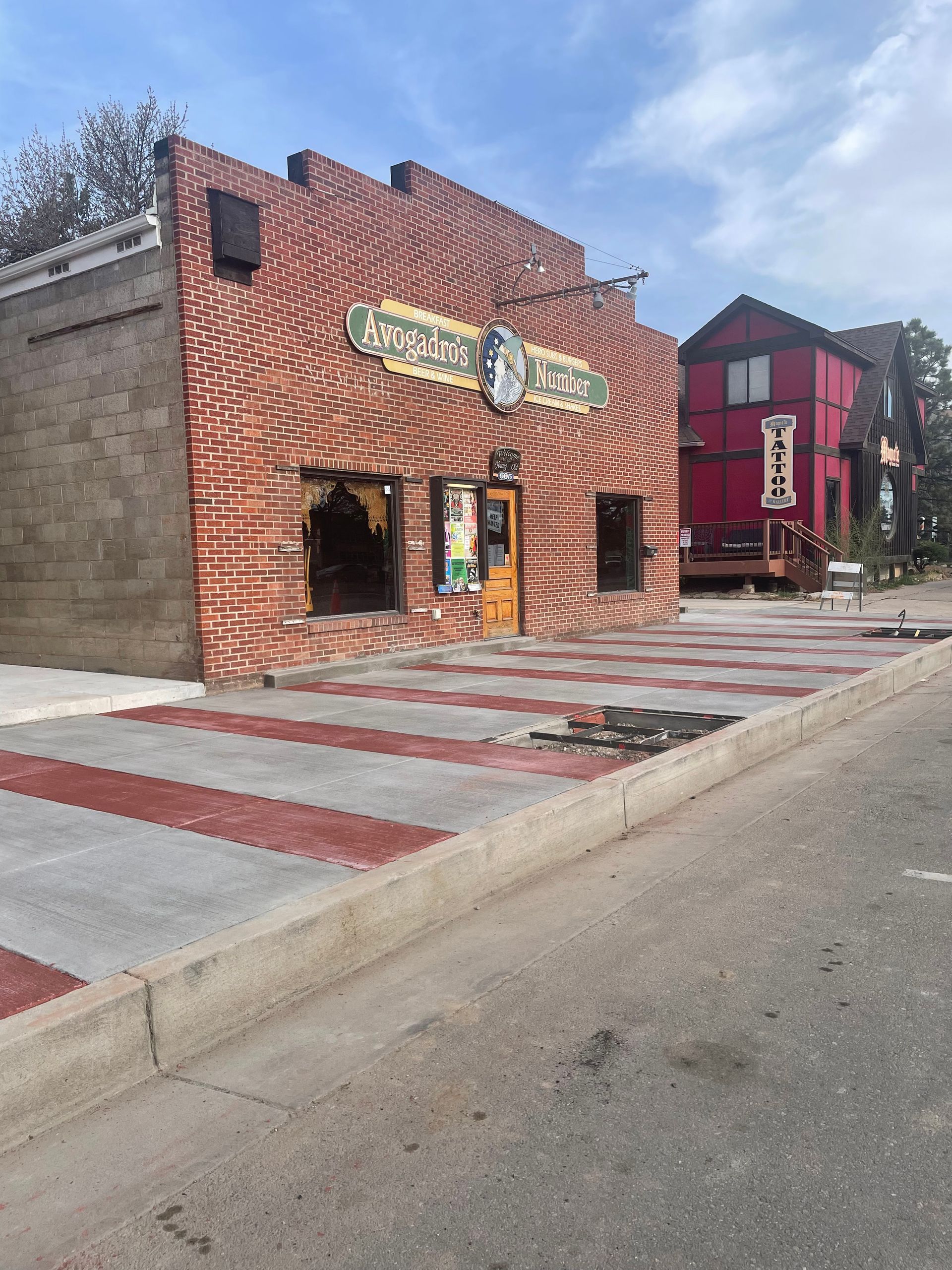 Old brick storefronts on a quiet street, with red and white striped sidewalk markings.