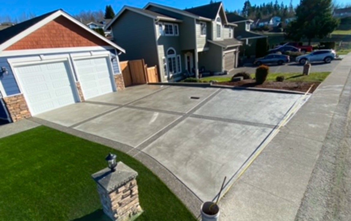 Suburban houses with a wide concrete driveway and two-car garage under a clear blue sky
