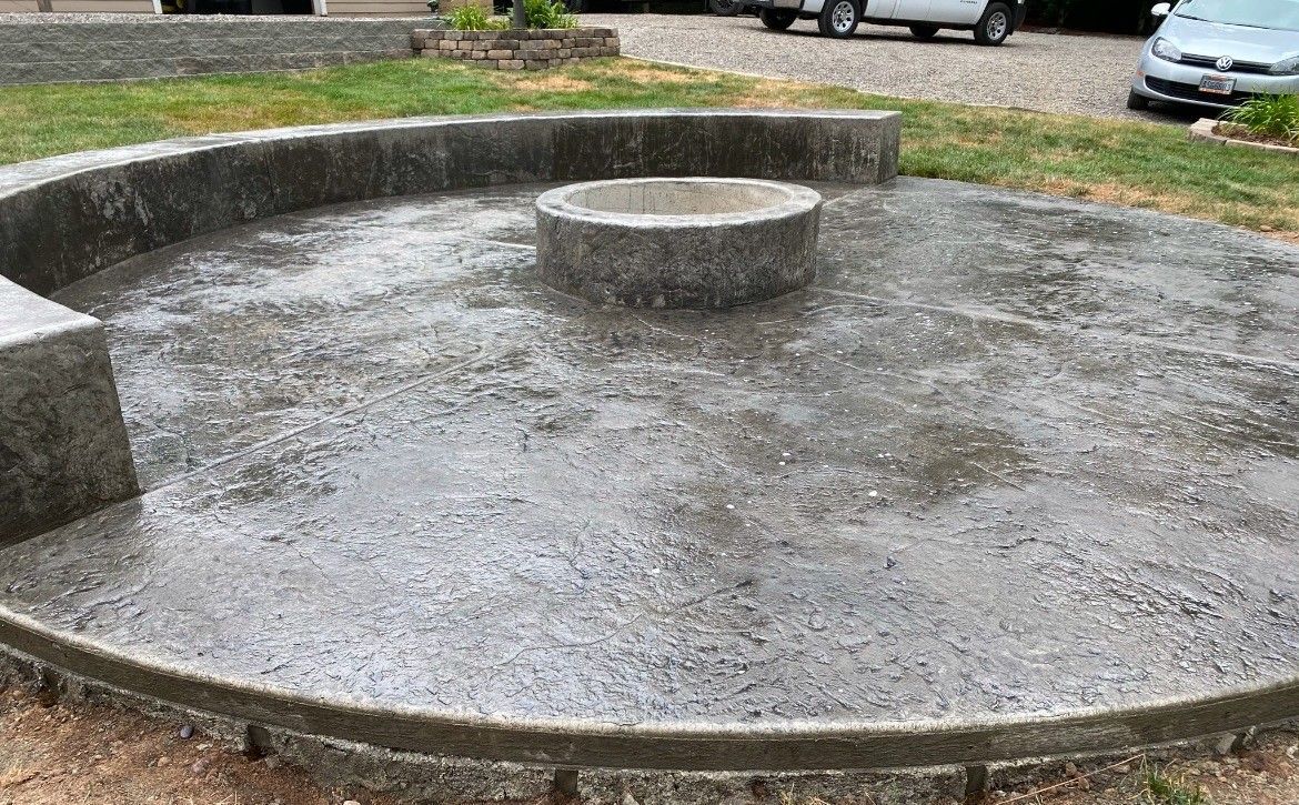 Empty circular concrete fountain basin with a raised center, outdoors on a gravel surface