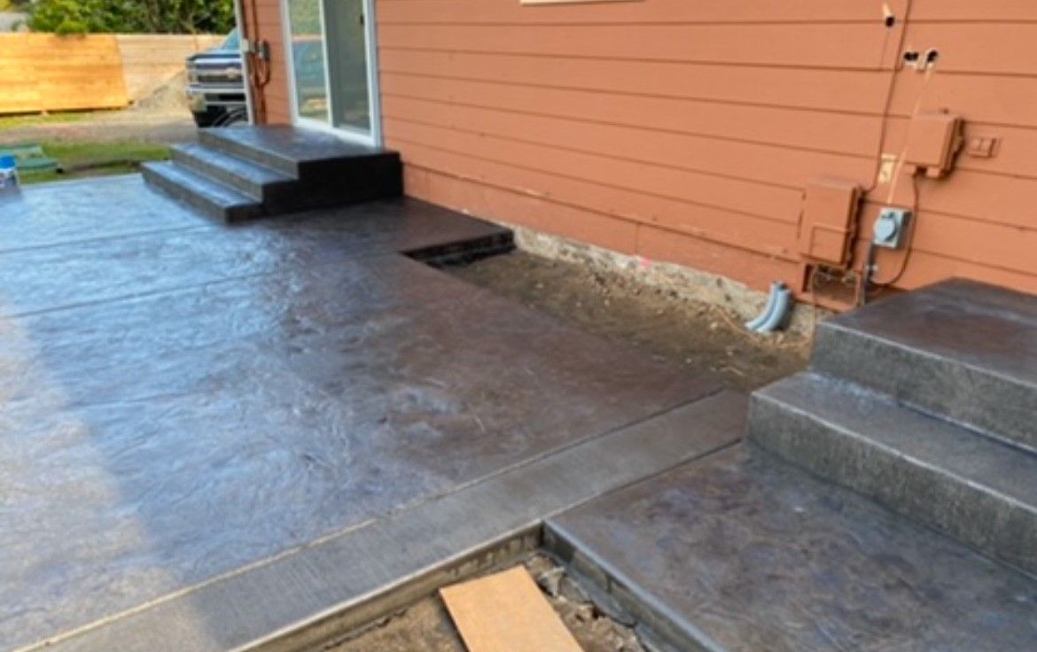 Accessible ramp with dark flooring leading to a house entrance beside steps and an orange exterior wall