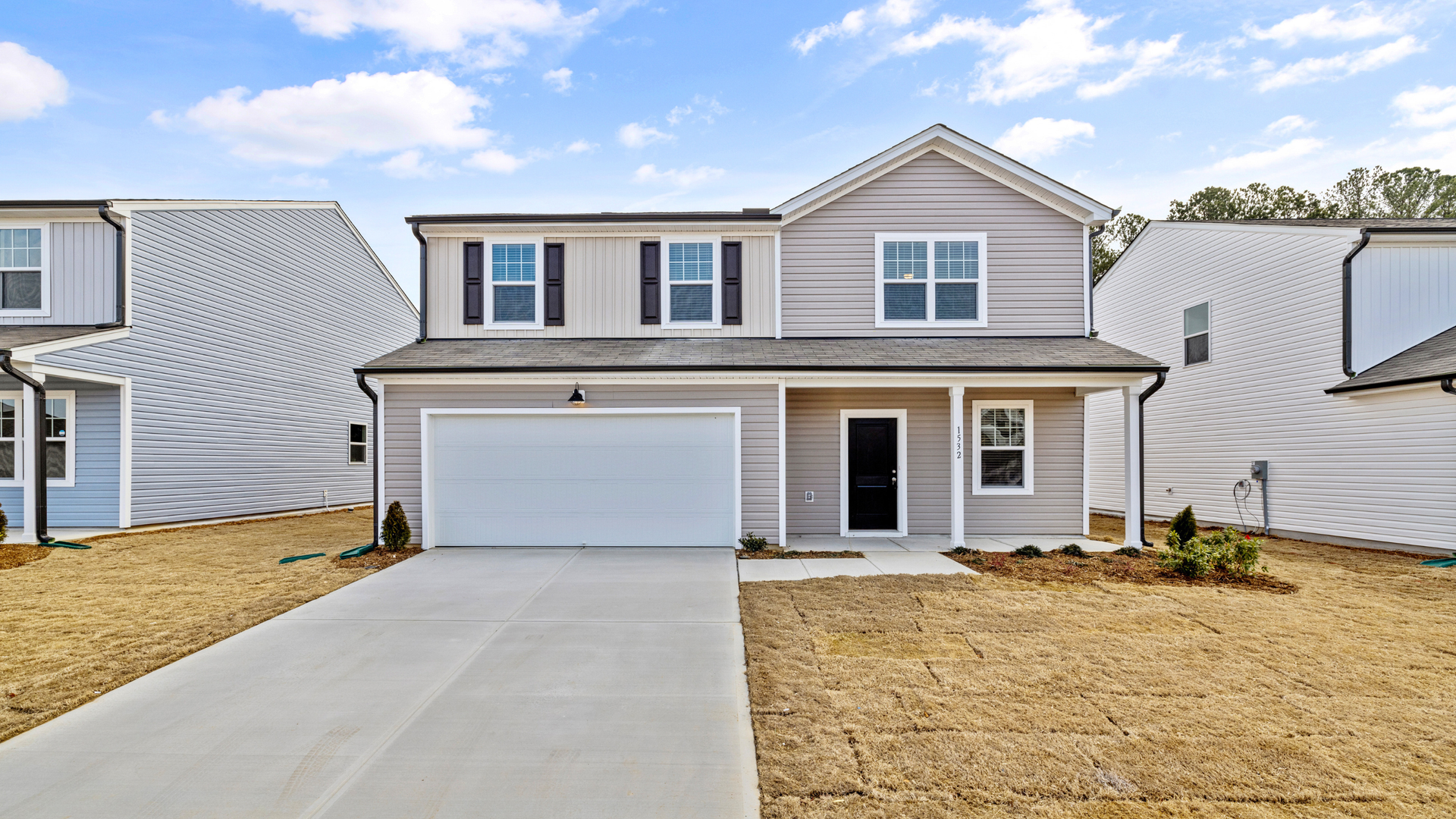 Suburban two-story gray house with white trim, double garage, and a concrete driveway