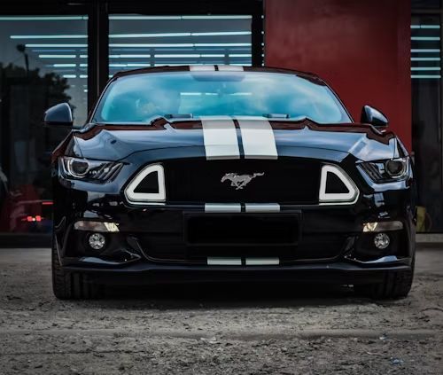 Black Ford Mustang with white stripes parked in front of a building.