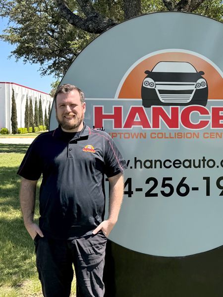 A man is standing in front of a hance auto sign.