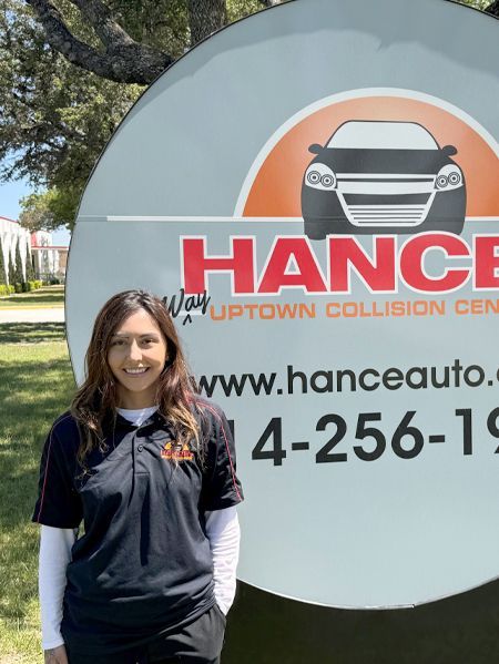 A woman is standing in front of a hance auto sign