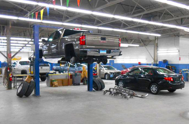 A truck is on a lift in a garage with other cars