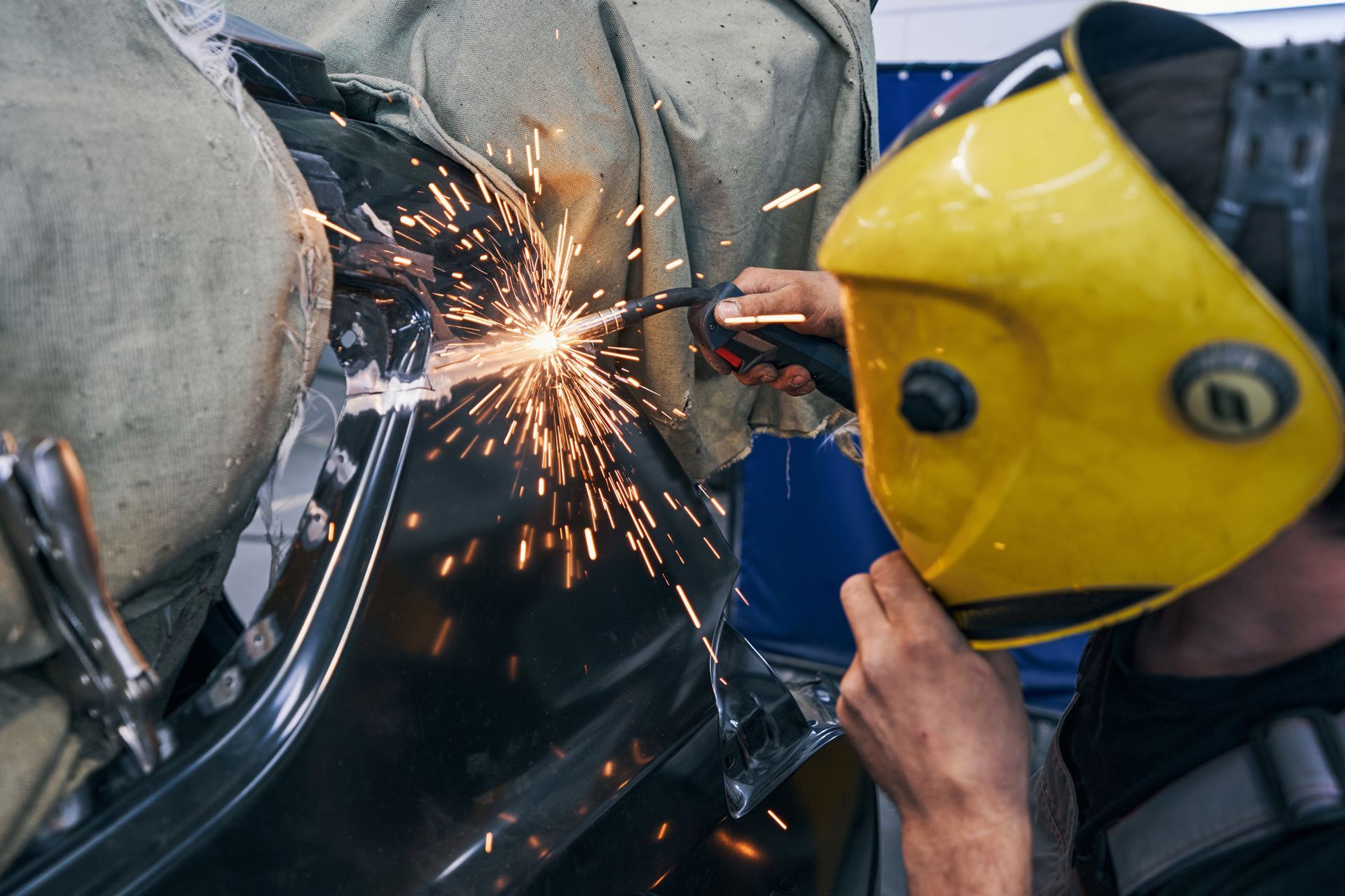 A man wearing a welding mask is welding a piece of metal.