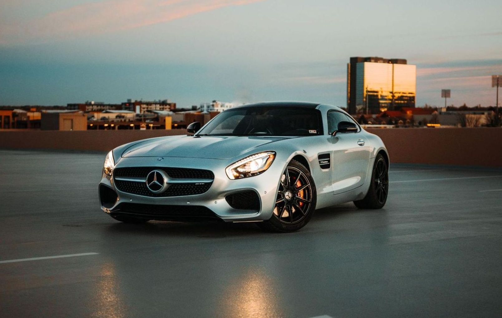 A silver mercedes benz gt is parked in a parking lot.