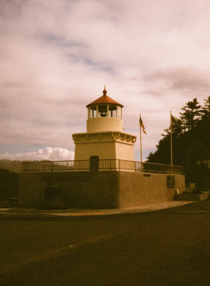 A vintage-style photo of the Cape Meares lighthouse in Oregon under a cloudy sky.