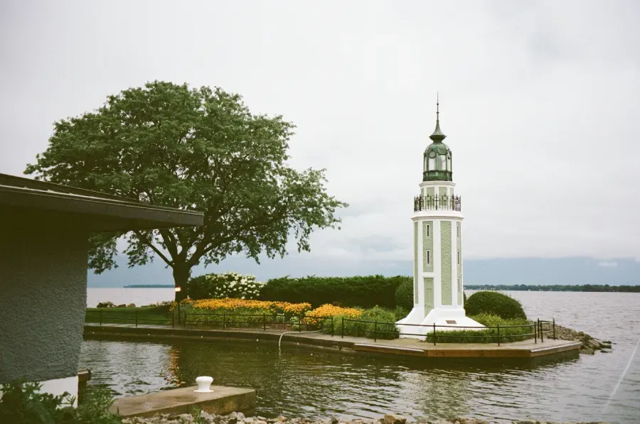 Bray's Point dink stands on a small, flower-lined peninsula beside a large tree by a lake.