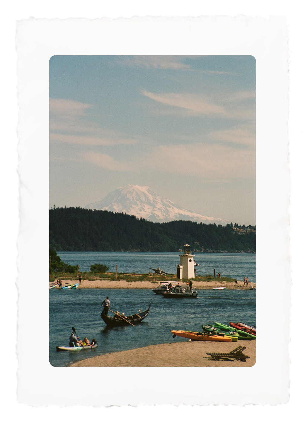 Kayaks on a blue lake by a small lighthouse, with a forested shoreline and pastel sky.