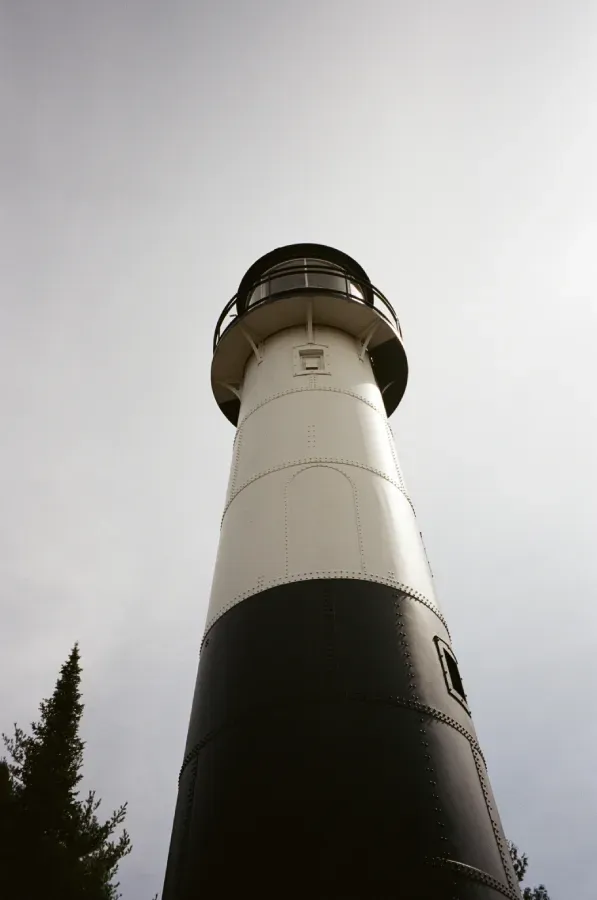 Tall, black and white lighthouse against a cloudy sky.