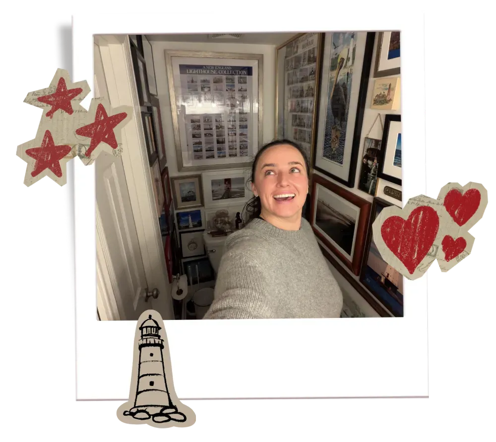 Charlee Remitz in a gray sweater smiles while taking a selfie inside her Lighthouse themed bathroom.
