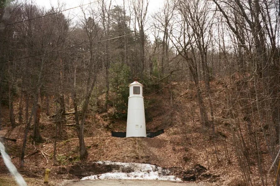 Munising Range rear dink structure sits in a wooded area with bare trees and some remaining snow on the ground.