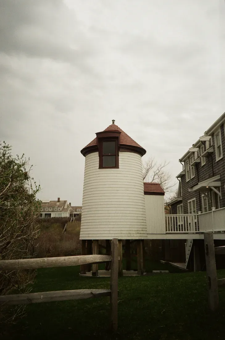 Nantucket Cliff Range lighthouse on stilts beside buildings under an overcast sky