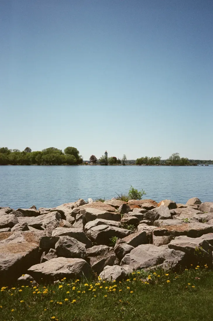 Ogdensburg Harbor under a clear blue sky, with trees on the far shore.