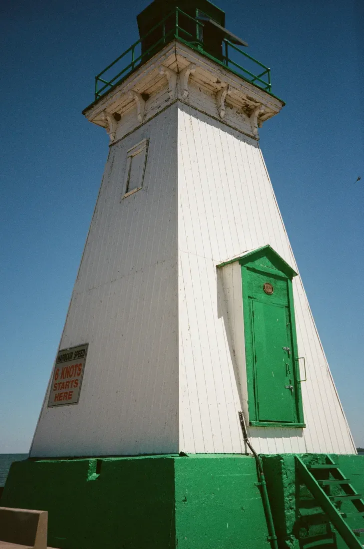 Port Dalhousie lighthouse with green door and base against blue sky