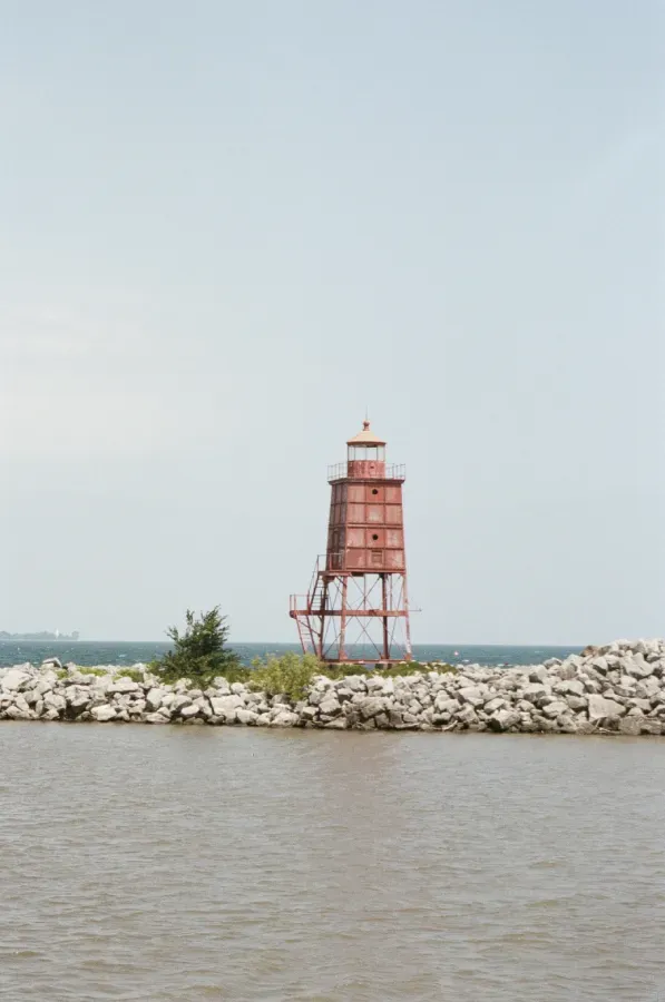 Racine Breakwater dink stands on a rocky breakwall surrounded by water under a bright, overcast sky.