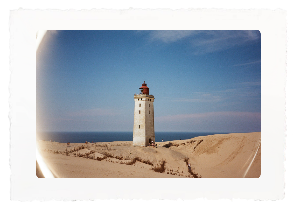 Lighthouse on sandy dunes under a clear blue sky by the sea