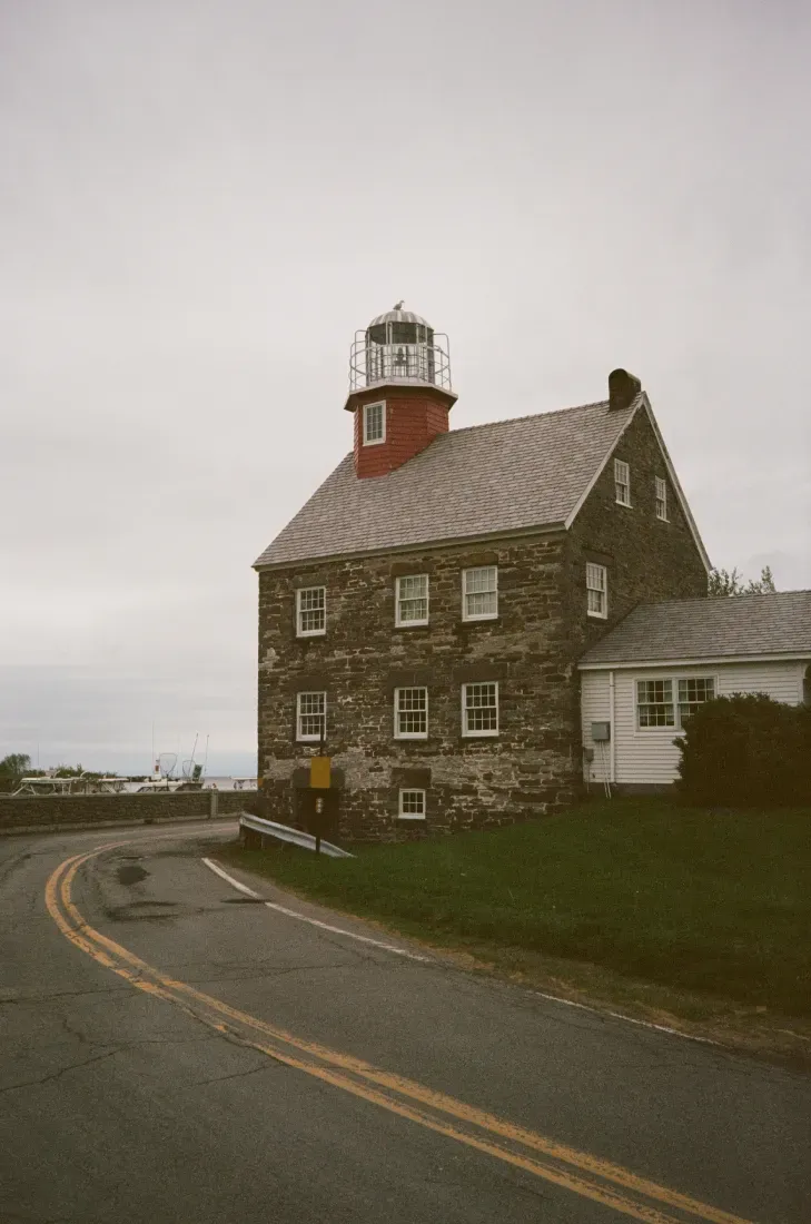 Salmon River lighthouse beside a curving road on a cloudy day