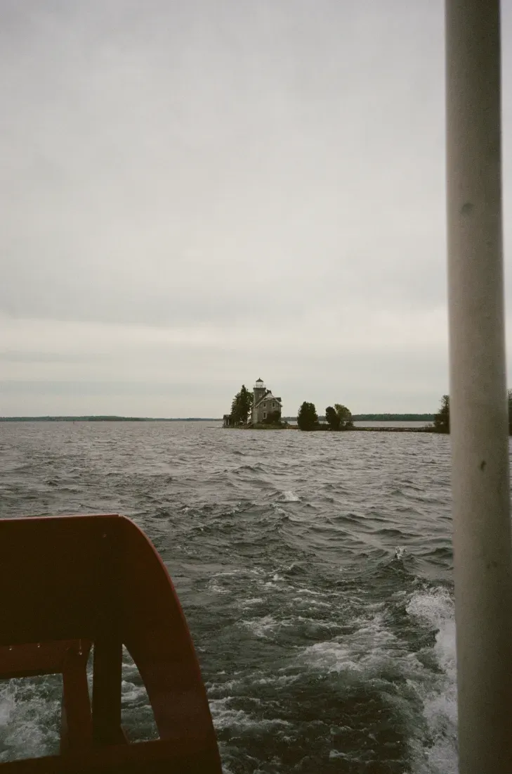 Sister Islands lighthouse in the distance of choppy gray under an overcast sky, seen from a boat